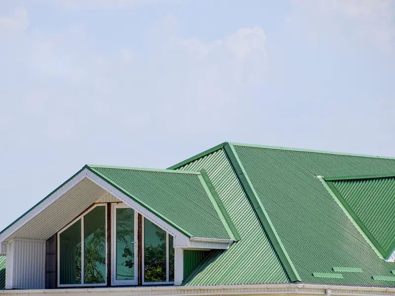 Green metal roof over a house with gables and a large window